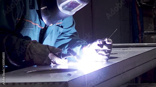 Static shot of worker welding stainless steel part, using TIG, MIG, welder, close up. The welder uses a mask to protect your eyes. Scene B. photo