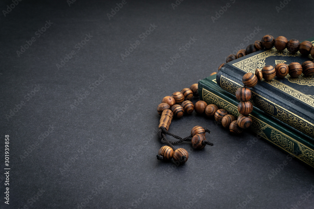Holy Quran with arabic calligraphy meaning of Al Quran and tasbih or rosary  beads on black background. Selective focus and crop fragment Stock Photo |  Adobe Stock