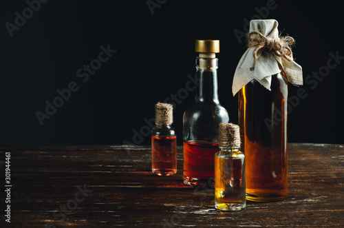 Several bottles with oil stand in a group on a wooden table.