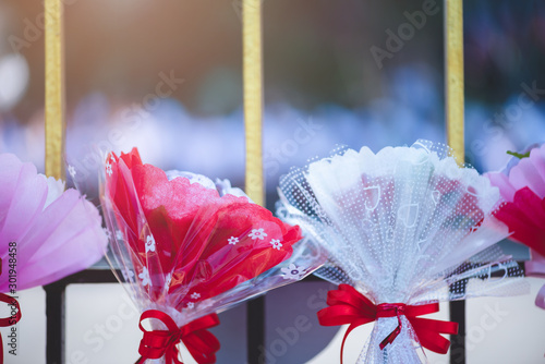 The bouquets of flowers wrapped in white, pink and red paper tied with a beautiful red ribbon. Which the trader put on the fence of the educational institution, allow people to buy for congratulation. photo