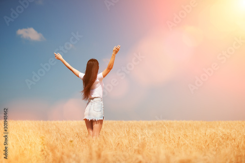 Happy woman enjoying the life in the field Nature beauty, blue sky, bright sun and field with golden wheat. Outdoor lifestyle. Freedom concept. Woman jump in summer field © Dmytro Sunagatov