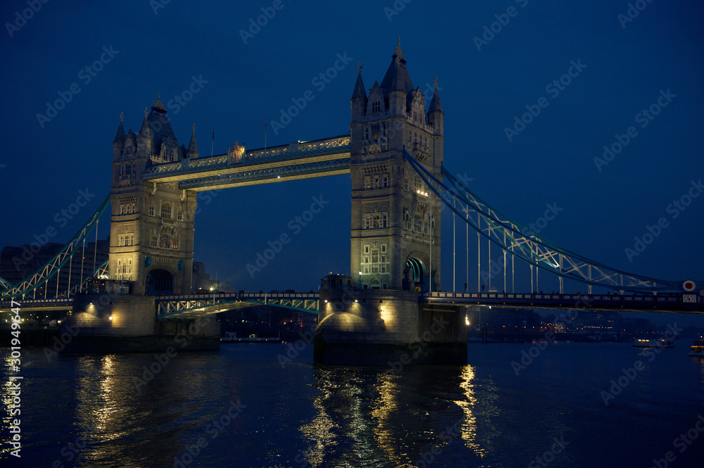 Scenic evening view of Tower Bridge with lights reflecting on the River Thames in London, UK