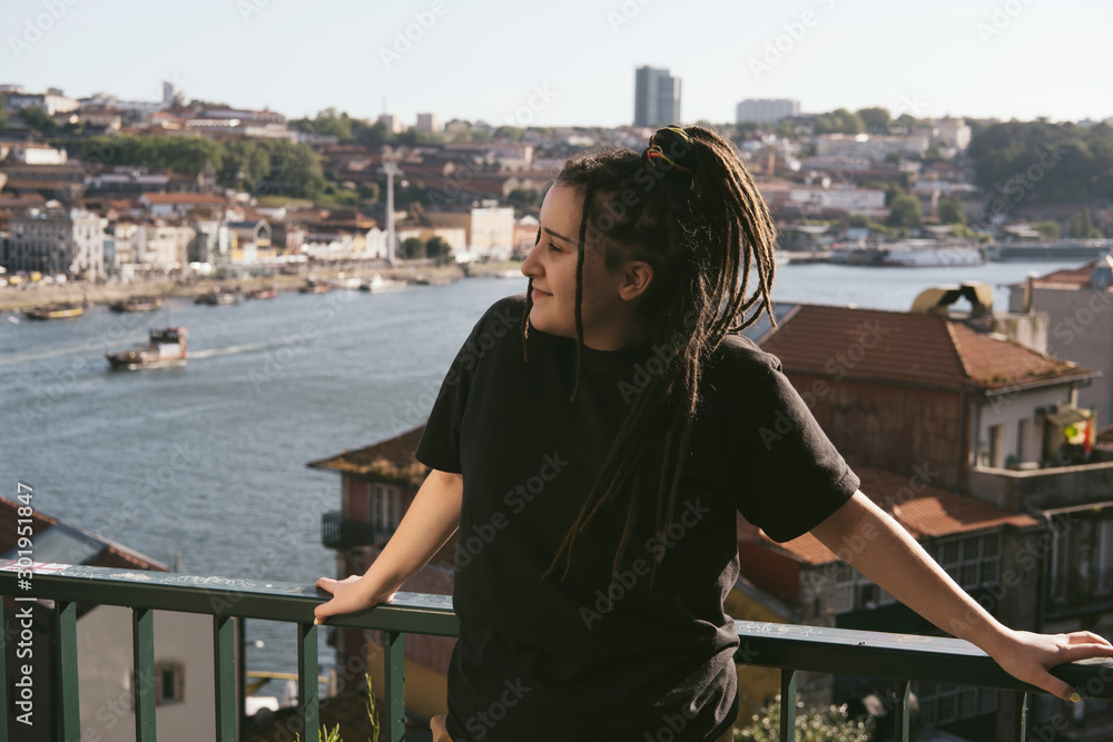 Young female wearing dreadlocks standing outdoors with river European city view