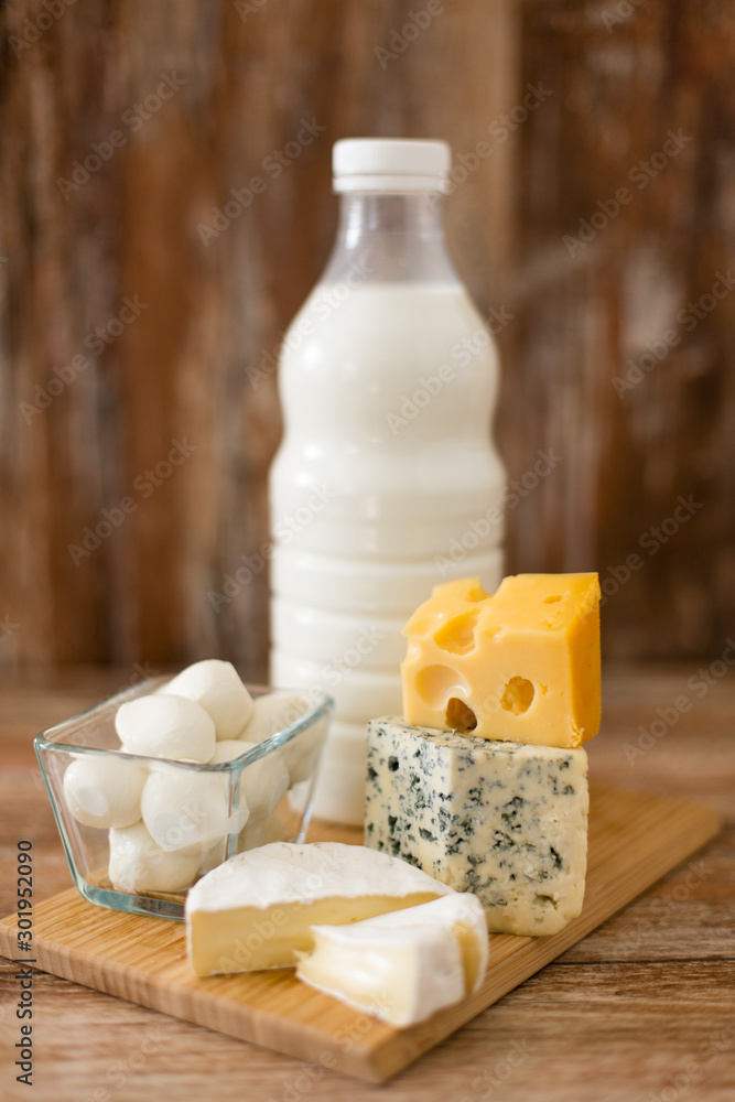 food and eating concept - different kinds of cheese and milk on wooden board food and eating concept - different kinds of cheese and milk on wooden board