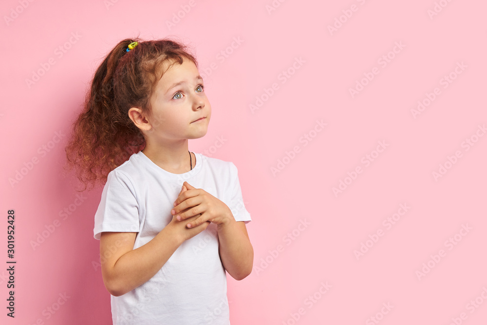 Redhaired child in white t-shirt stand looking up, dreaming about new toy isolated over pink background Redhaired child in white t-shirt stand looking up, dreaming about new toy isolated over pink background