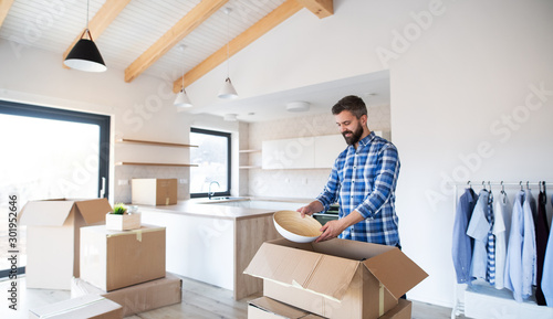Mature man with boxes moving in new unfurnished house.