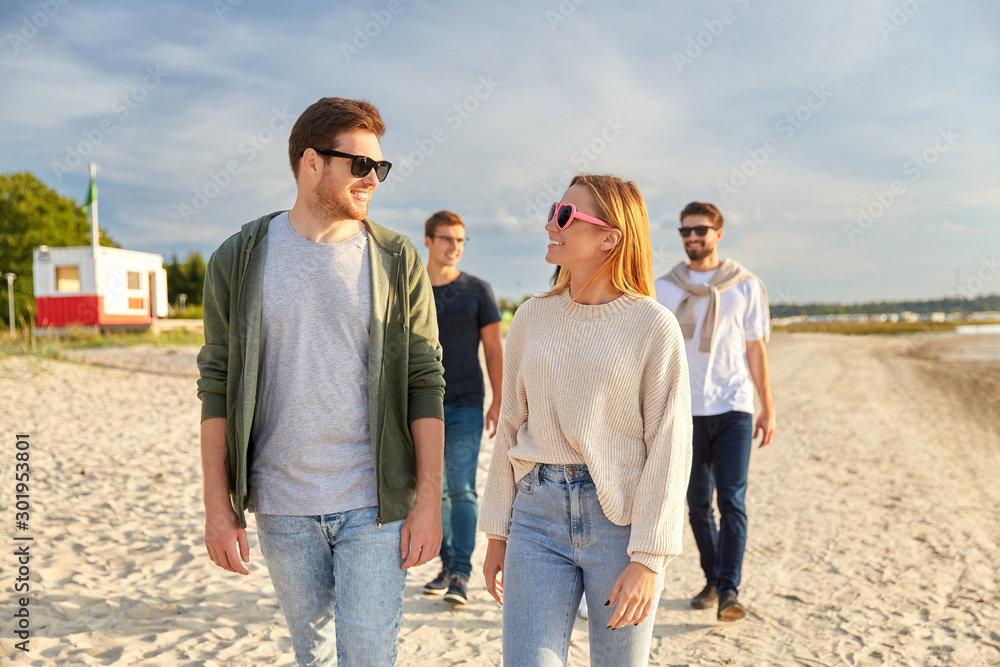 friendship, leisure and people concept - group of happy friends walking along beach in summer friendship, leisure and people concept - group of happy friends walking along beach in summer
