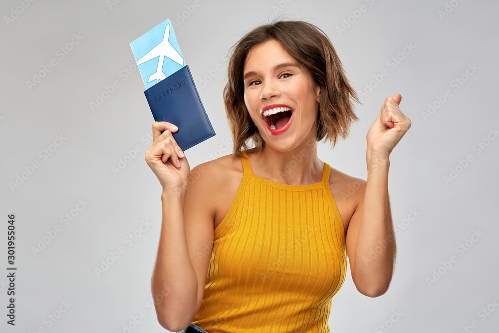 travel, tourism and vacation concept - happy laughing young woman in mustard yellow top with air ticket and passport over grey background - obrazy, fototapety, plakaty 