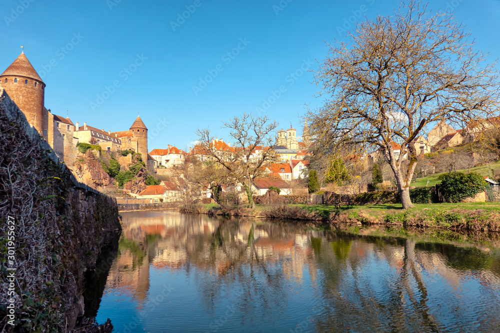 View of the city of Semur-An-Osua from the banks of the Armankon River in springtime. There are castle buildings, a riverbank and houses traditional for the region. Burgundy. France.