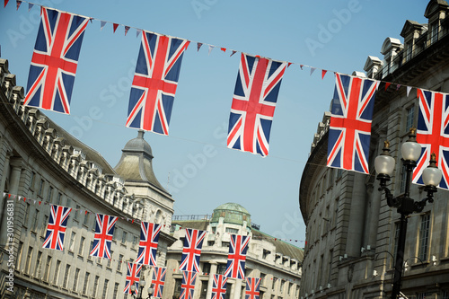 British Union Jack flag decorations hanging across the curving streets of London, UK under bright blue sky