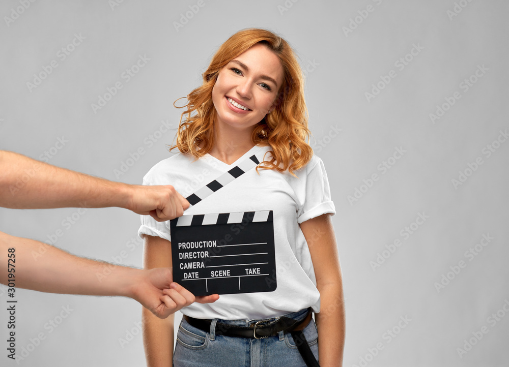 production, filmmaking and entertainment concept - happy woman or actress at studio casting and hands with clapperboard over grey background