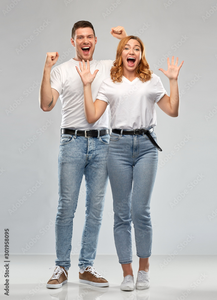 emotions and people concept - portrait of happy couple in white t-shirts celebrating success over grey background emotions and people concept - portrait of happy couple in white t-shirts celebrating success over grey background