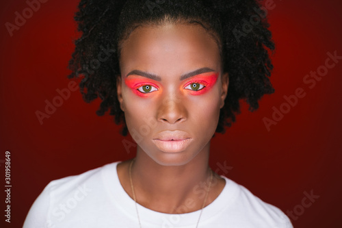 Studio portrait of fashion African female model with make up. Red coloured background