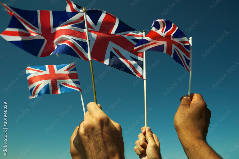 Group of patriotic hands waving Union Jack British flags in bright blue sky at a Brexit protest in London - obrazy, fototapety, plakaty 
