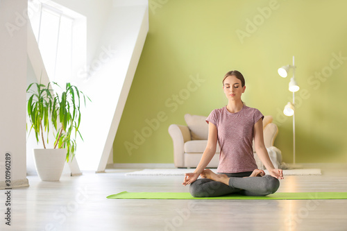 Fototapeta Naklejka Na Ścianę i Meble -  Young woman practicing yoga at home