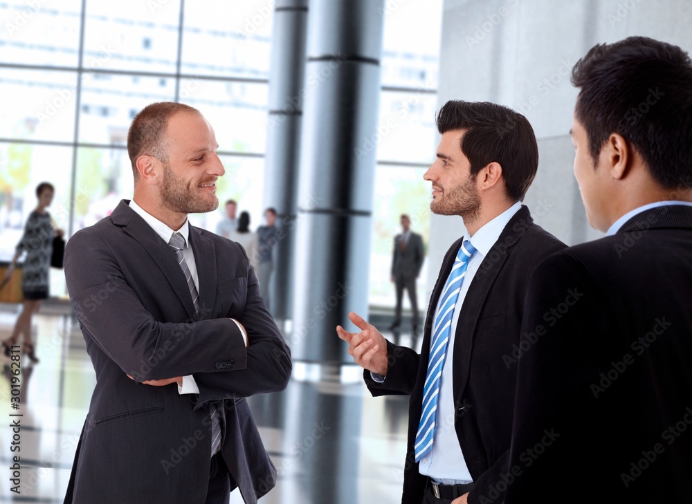 Smiling businessmen talking inside office building Smiling businessmen talking inside office building