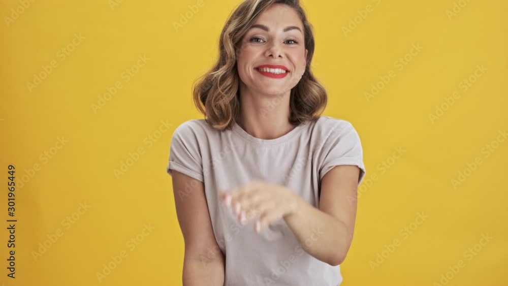 Charming young woman with red lips sending an air kiss while looking at the camera over yellow background isolated Charming young woman with red lips sending an air kiss while looking at the camera over yellow background isolated