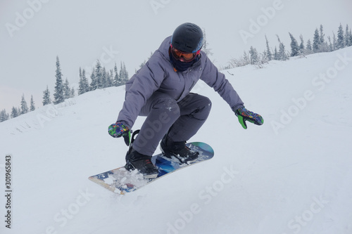 Young snowboarder riding in the mountains on a snowboard.