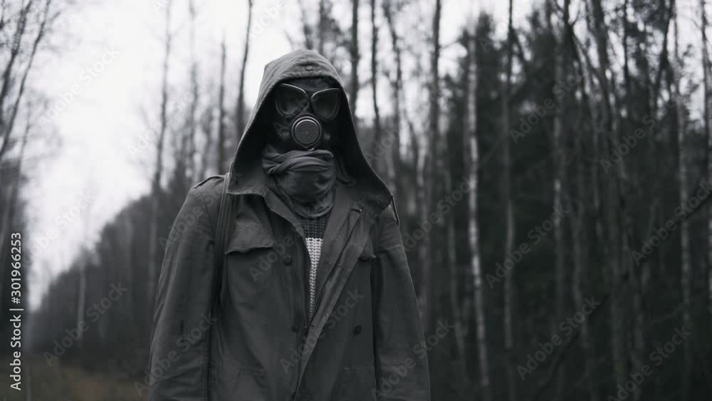 Man in military clothes and gas mask standing on old railway in empty dead forest. Stalker concept, male survivor after nuclear or chemical war. Post apocalyptic world. Stedicam shot Man in military clothes and gas mask standing on old railway in empty dead forest. Stalker concept, male survivor after nuclear or chemical war. Post apocalyptic world. Stedicam shot