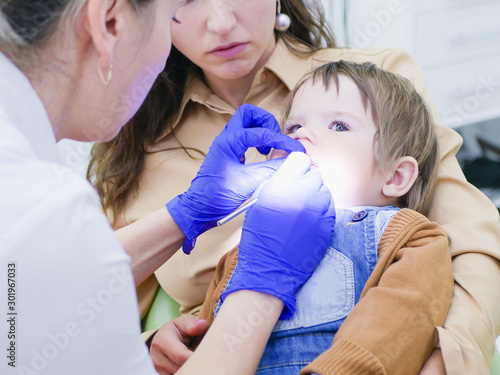 Childrens dentistry. Dental examination. Dentist treats the boys teeth. Female dentist treats teeth. Boy 0-1 age. Oral health. photo