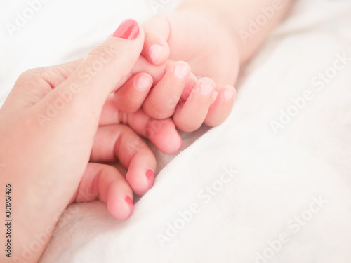 Mom holds the hand of a newborn baby. Close-up. A place to write. Placing text. defocusing. Baby s hand holding finger to mom.