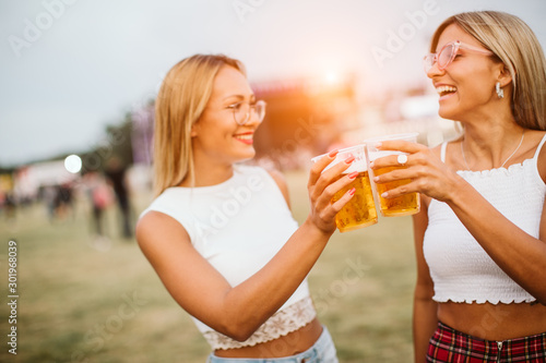 Two girls toasting with beer at music festival