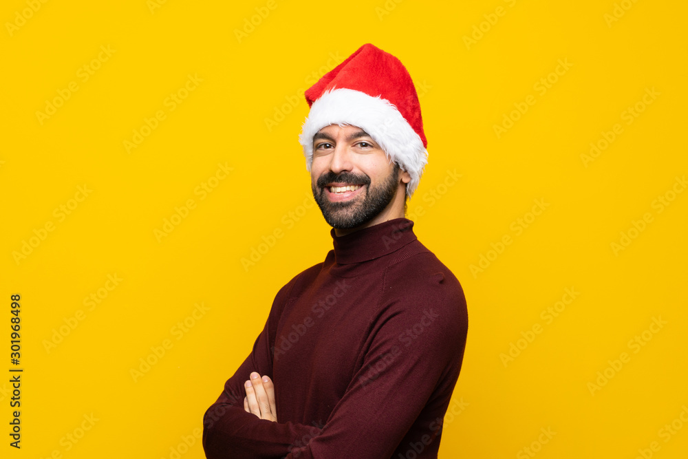 Man with christmas hat over isolated yellow background with arms crossed and looking forward Man with christmas hat over isolated yellow background with arms crossed and looking forward