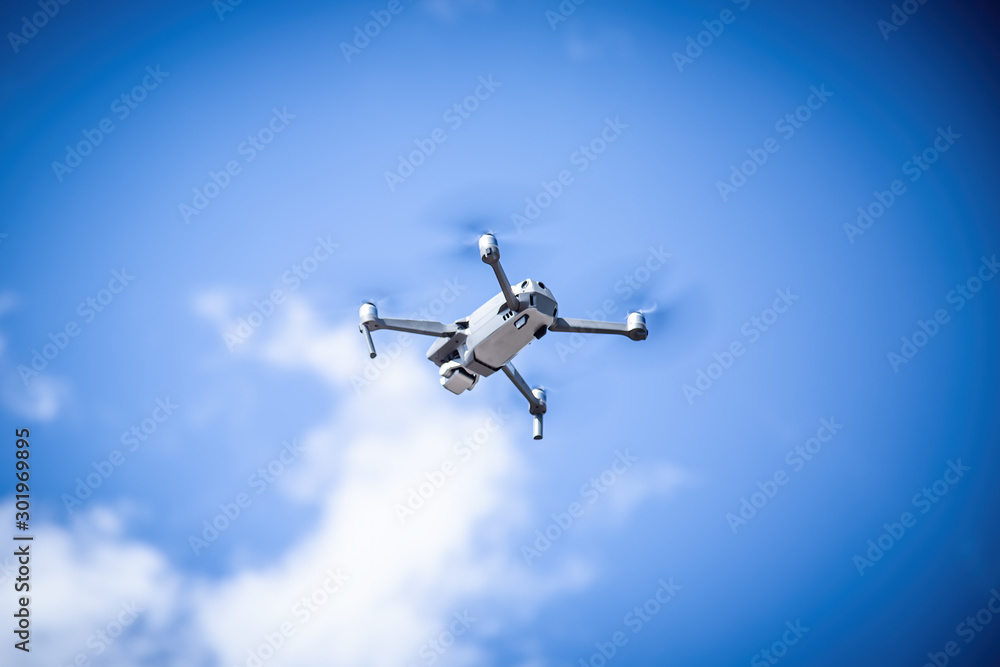Gray drone flies against the sky with clouds
