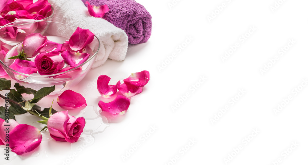 Pink roses petals in bowl with towels and pure water over white.. Spa and wellness concept Pink roses petals in bowl with towels and pure water over white.. Spa and wellness concept