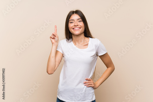 Pretty young girl over isolated background showing and lifting a finger in sign of the best