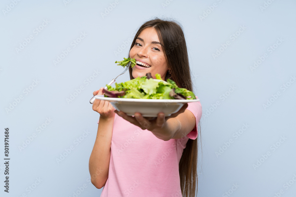 Young woman with salad over isolated blue background Young woman with salad over isolated blue background