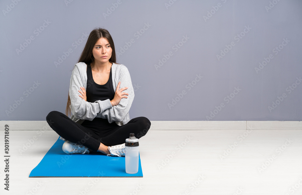 Young sport woman sitting on the floor with mat thinking an idea Young sport woman sitting on the floor with mat thinking an idea