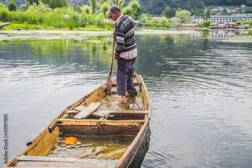 An old man removing water which has entered the broken boat