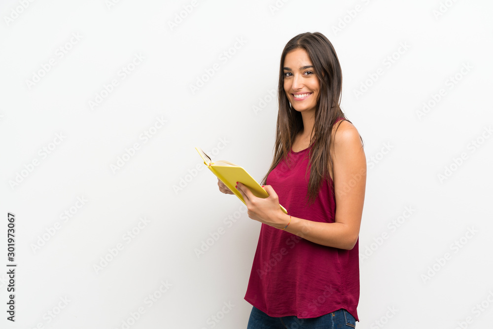 Young woman over isolated white background holding and reading a book Young woman over isolated white background holding and reading a book
