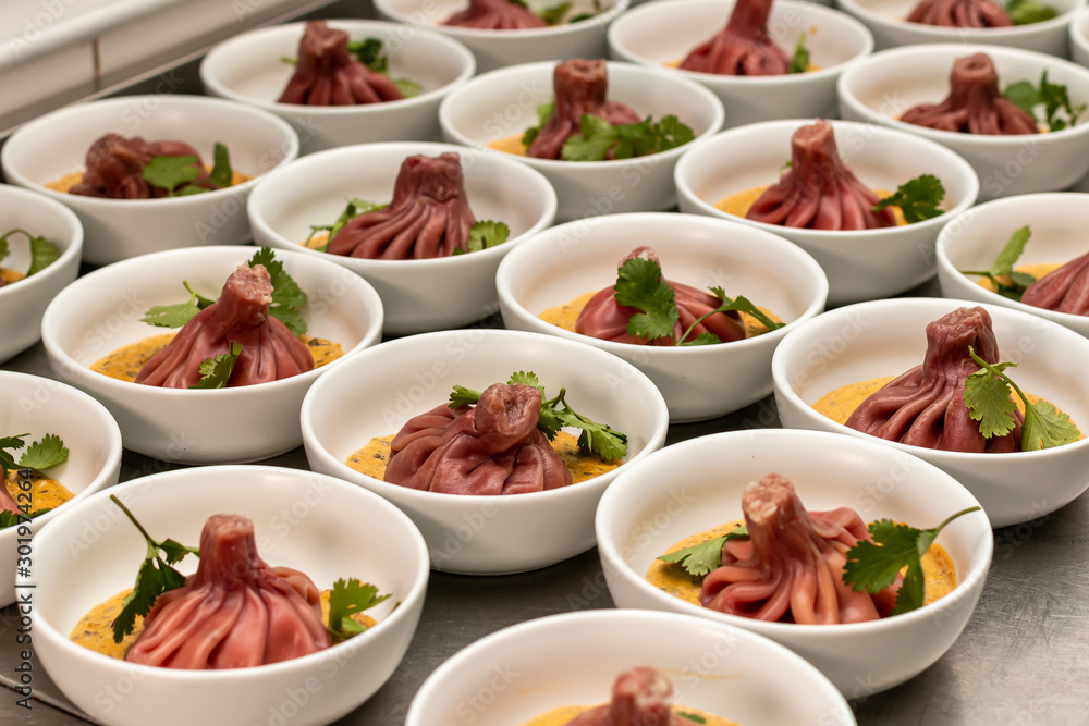Many beetroot khinkali on mashed potatoes in plates in a restaurant kitchen. Many beetroot khinkali on mashed potatoes in plates in a restaurant kitchen.