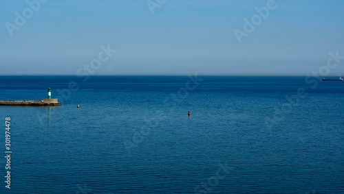 Green striped light house with boat on the sea, copy space in blue sky