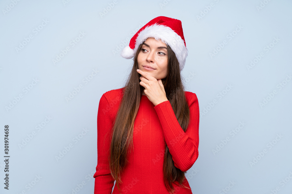 Girl with christmas hat over isolated blue background thinking an idea Girl with christmas hat over isolated blue background thinking an idea