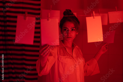 photographer on work, amateur, hobbyist or professional Young girl developing photos in a dark room. Retro style photography