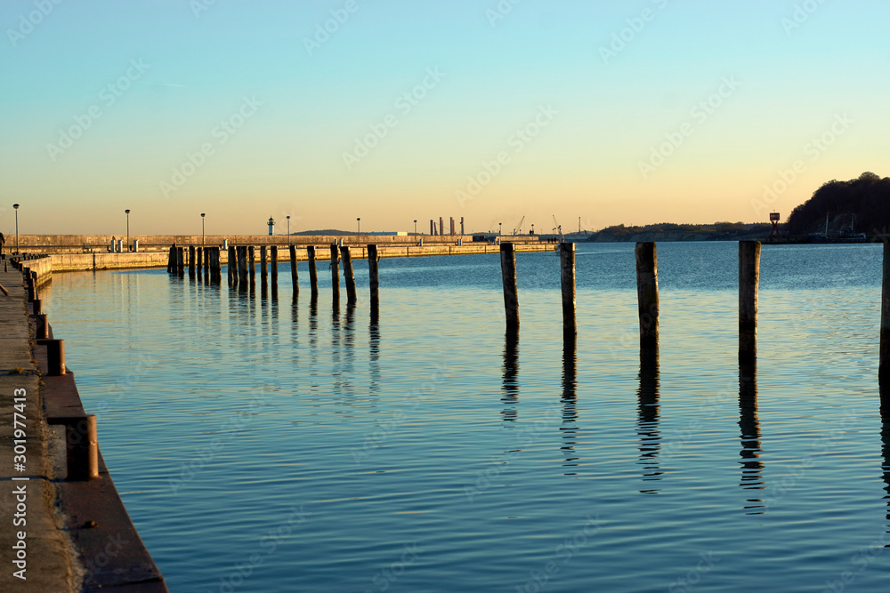 Dock pillars with reflection at sun set, romantic vacation at the beach, German getaway