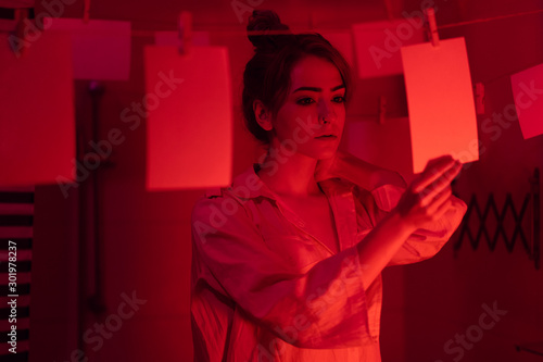 Tablou pe pânză photographer on work, amateur, hobbyist or professional Young girl developing photos in a dark room