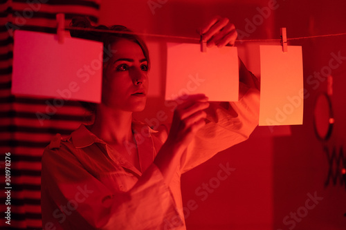 photographer on work, amateur, hobbyist or professional Young girl developing photos in a dark room. Retro style photography