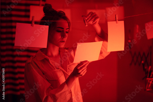 photographer on work, amateur, hobbyist or professional Young girl developing photos in a dark room. Retro style photography