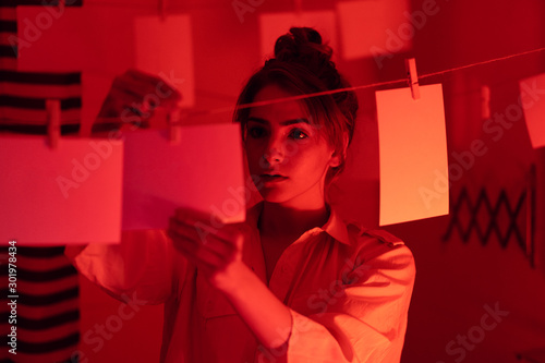 Фотография photographer on work, amateur, hobbyist or professional Young girl developing photos in a dark room
