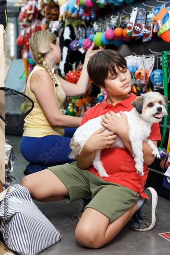 Cheerful small boy with havanese pup while shopping with mother in pet store