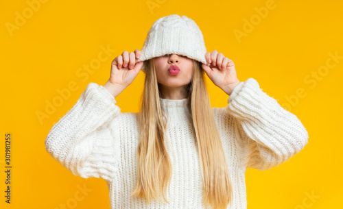 Konstfotografi Girl with kissing lips pulling down woollen hat