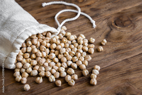 Dry chickpeas in a textile bag on a wooden background. photo