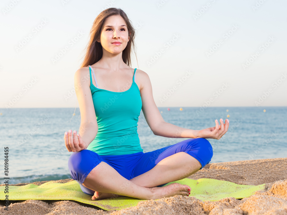 Female 20-25 years old is sitting and practicing meditation in blue T-shirt