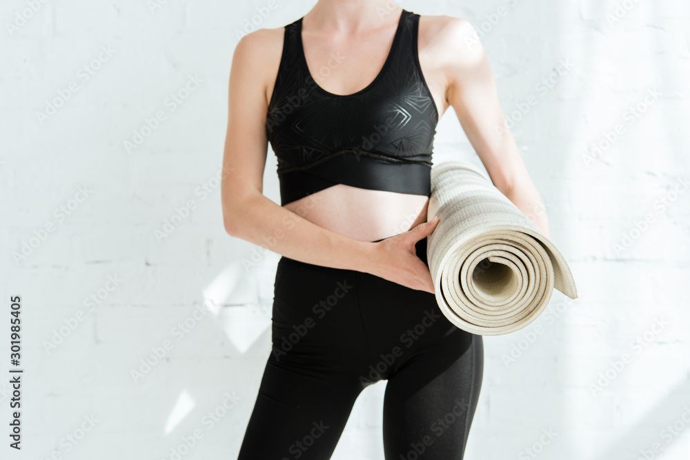 cropped view of woman in sportswear holding yoga mat cropped view of woman in sportswear holding yoga mat