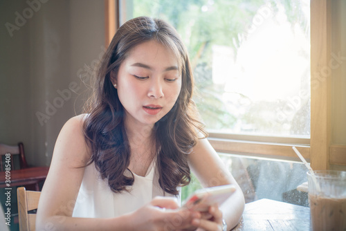 Business asian women use smartphone sitting in coffee shop