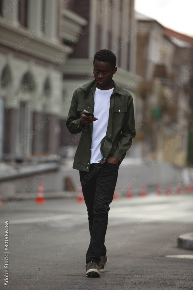 African man using mobile phone walking in a city African man using mobile phone walking in a city
